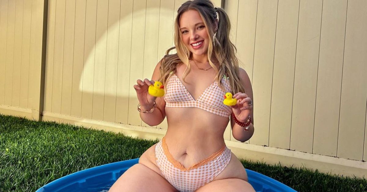 Bikini-clad woman holding yellow ducks in a pool, smiling, grassy outdoor setting.