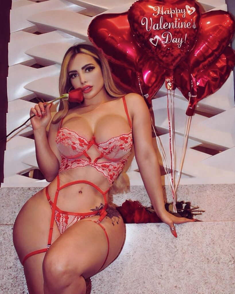 A model in lingerie poses with a red heart, holding an umbrella. The image conveys "Happy Valentine's Day!"